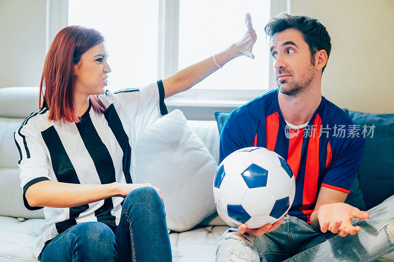 一对情侣在电视上看足球比赛，兴奋地看着对方