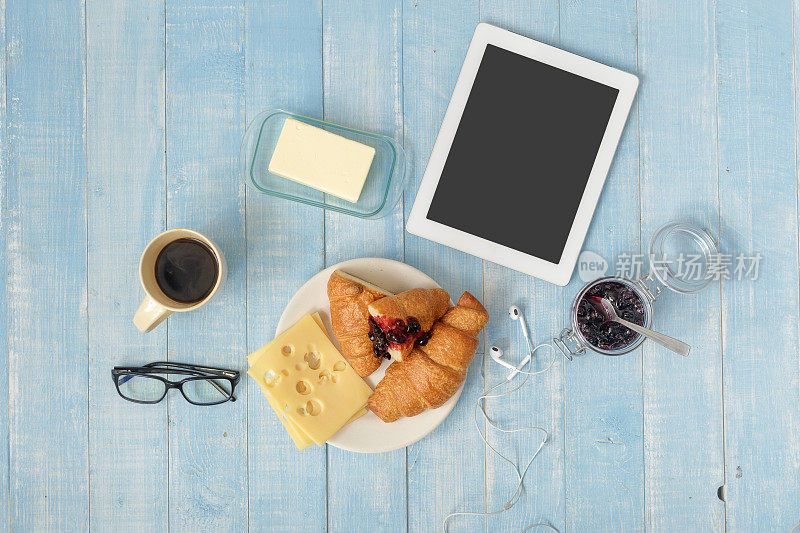 早餐桌上有药片，咖啡，羊角面包，奶酪，果酱和黄油在家庭厨房，俯视图