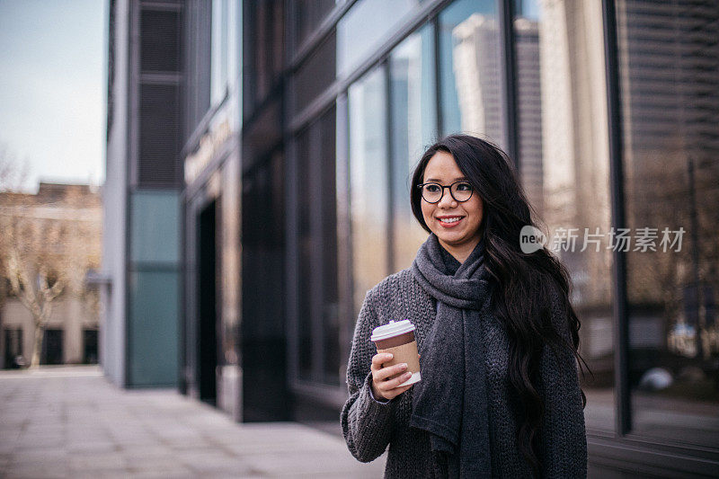 在街上拿着咖啡杯的女士