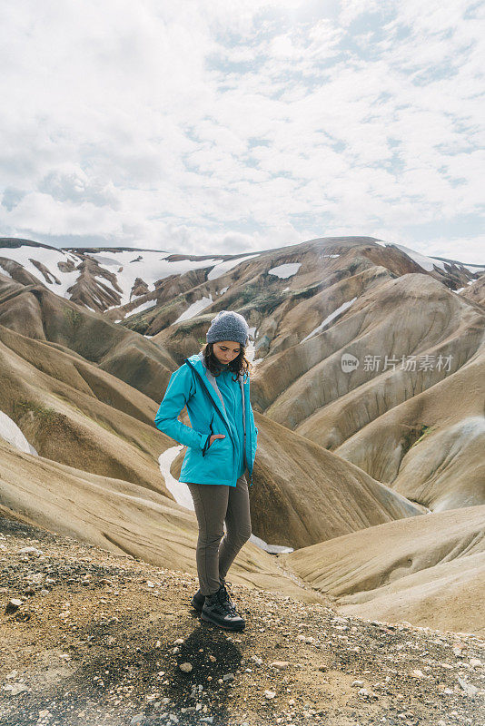 在冰岛的Landmannalaugar，一名妇女在彩色山脉附近徒步旅行