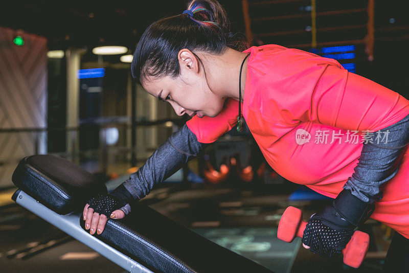 亚洲妇女在健身俱乐部用哑铃锻炼