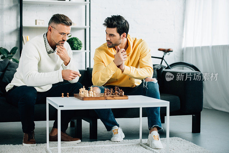 沉思的儿子和成熟的父亲周末一起在家里下棋