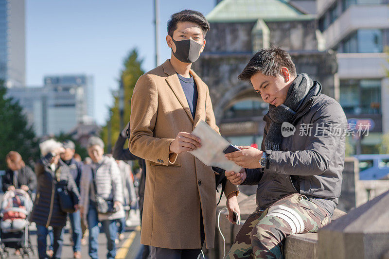 年轻的亚洲男子和日本朋友寻找旅游地点使用手机和花时间在亚洲旅行