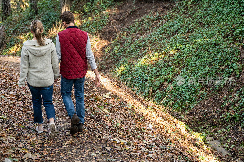 牵手在森林里散步的年轻夫妇