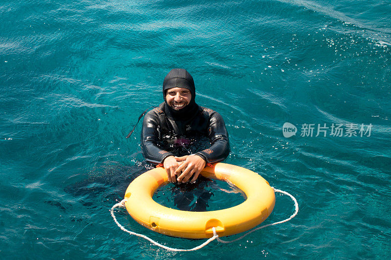 英俊性感的潜水员在蔚蓝的大海的背景。水救援行动。在红海里浮潜和水肺潜水。