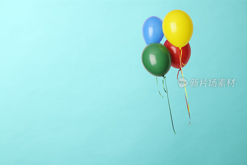 四个五颜六色的气球在蓝色背景的半空中