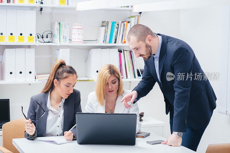 两个年轻的女商人和她的老板坐在会议室的办公室里讨论他们正在进行的项目。