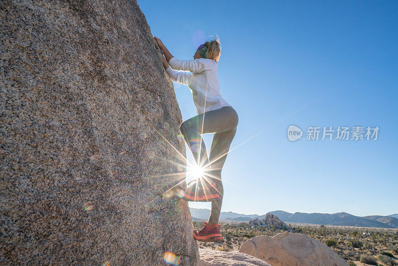 年轻女子攀登陡峭的巨石;人的户外活动概念