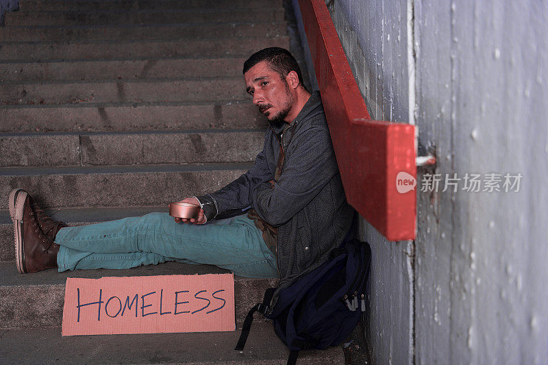 无家可归的乞丐坐在城市的地下等待捐赠