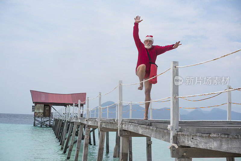 一名男子扮成圣诞老人，跳上通往马来西亚婆罗洲海滩的木船码头。