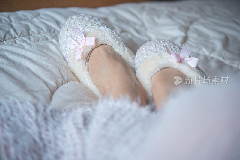 女人的腿在床上毛绒拖鞋的特写