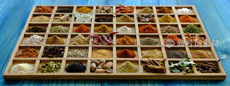 各种彩色的，有机的，干燥的，充满活力的印度食物香料在一个古老的绿松石色的背景木托盘，与大气的照明。