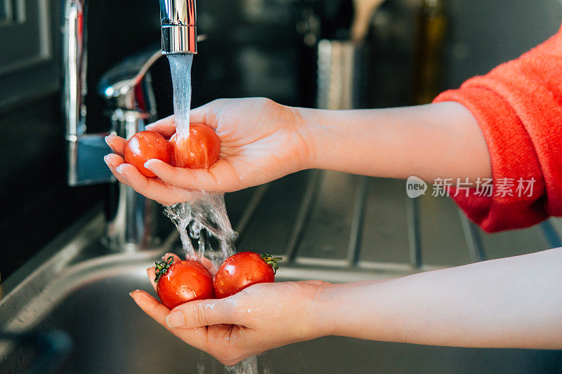 女人的手在厨房洗西红柿的特写照片