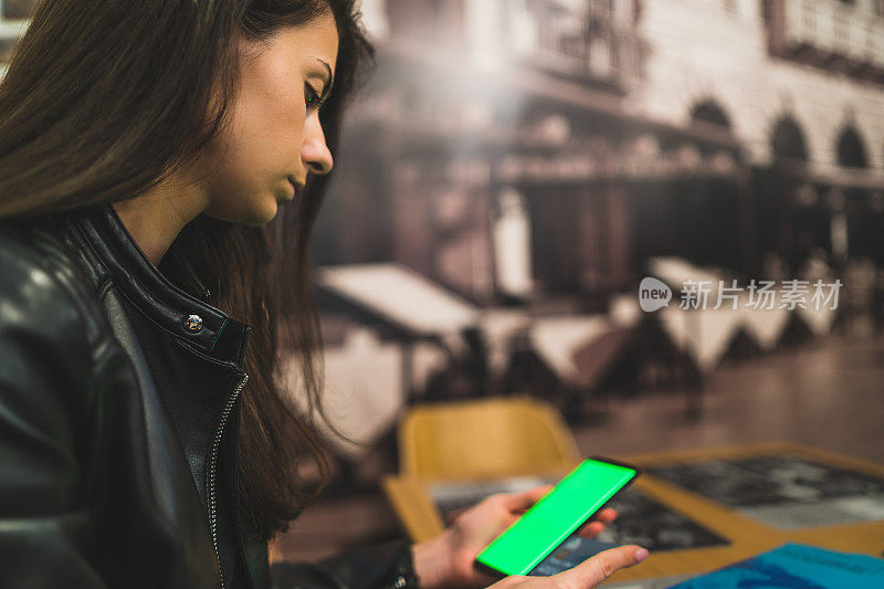 女孩在咖啡店用绿屏智能手机