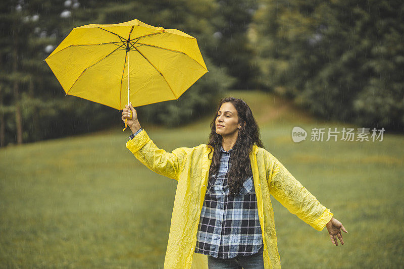 女人穿着雨衣，撑着雨伞，在雨天行走