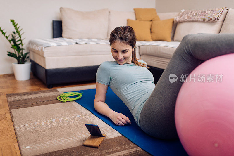 年轻女子在家用手机应用练普拉提