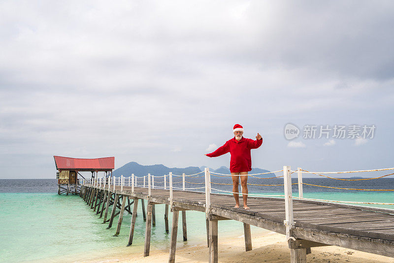 背景:圣诞老人在马来西亚婆罗洲的沙滩上走出大海。