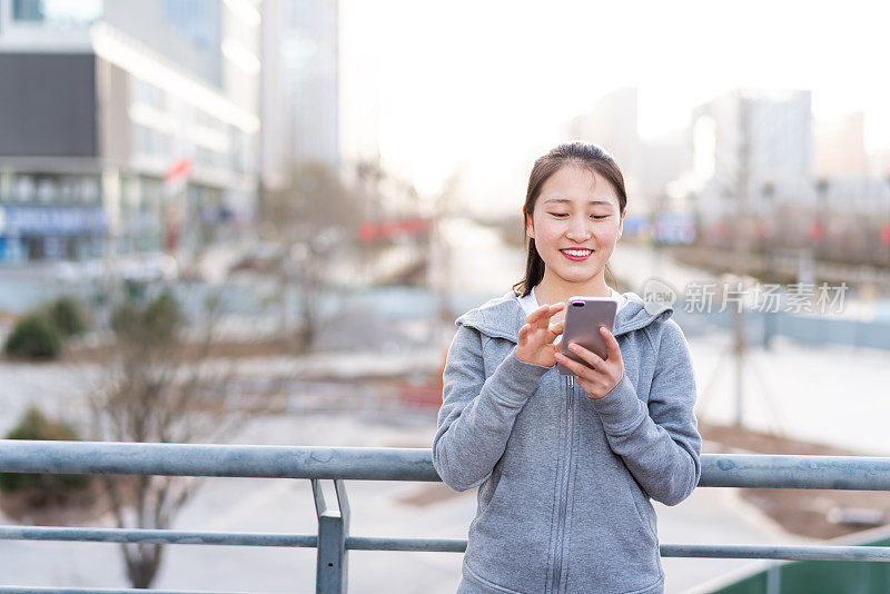 亚洲年轻女子在城市公共广场使用手机