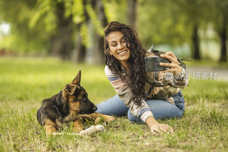 一个女人和她的狗在用手机自拍