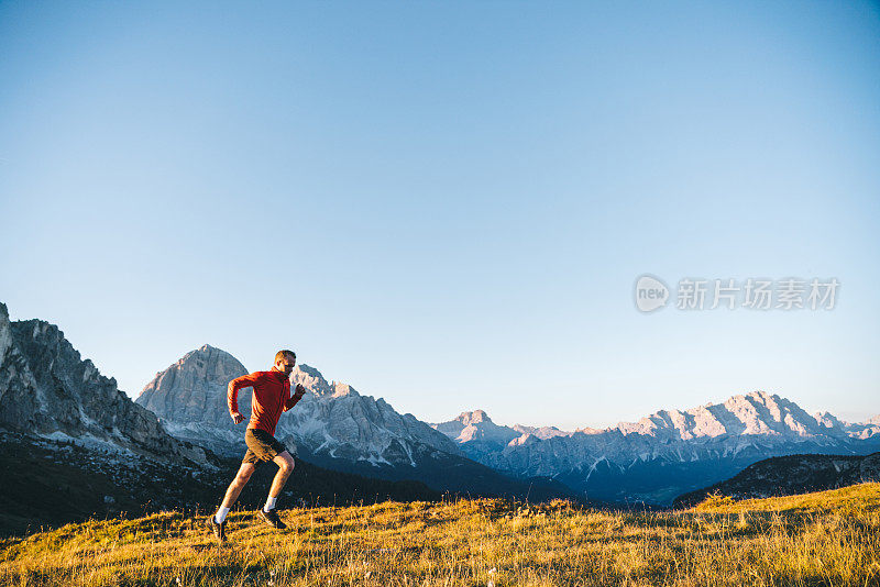 赛跑者在日出时穿过高山草甸