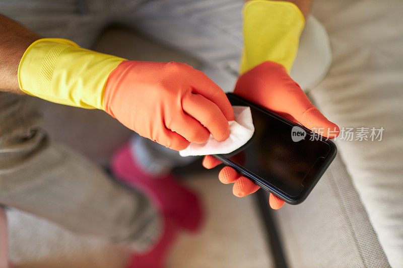 一名男子戴着橡胶手套，用消毒湿巾消毒和清洁手机的各种照片
