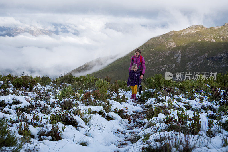 母亲和女儿一起在雪地里徒步旅行