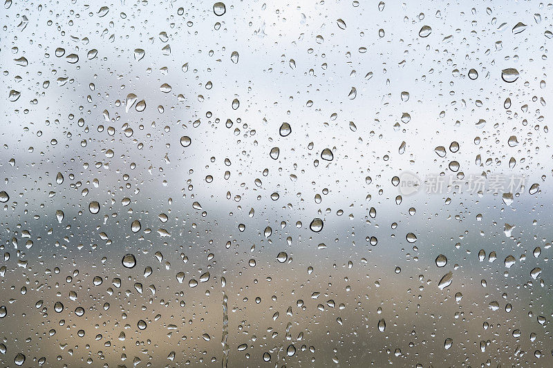 雨滴落在窗户玻璃外面的纹理背景水奇妙的大雨天与天空的云在城市蓝色绿色模糊的灯光抽象的视图阳光享受放松的自然墙纸