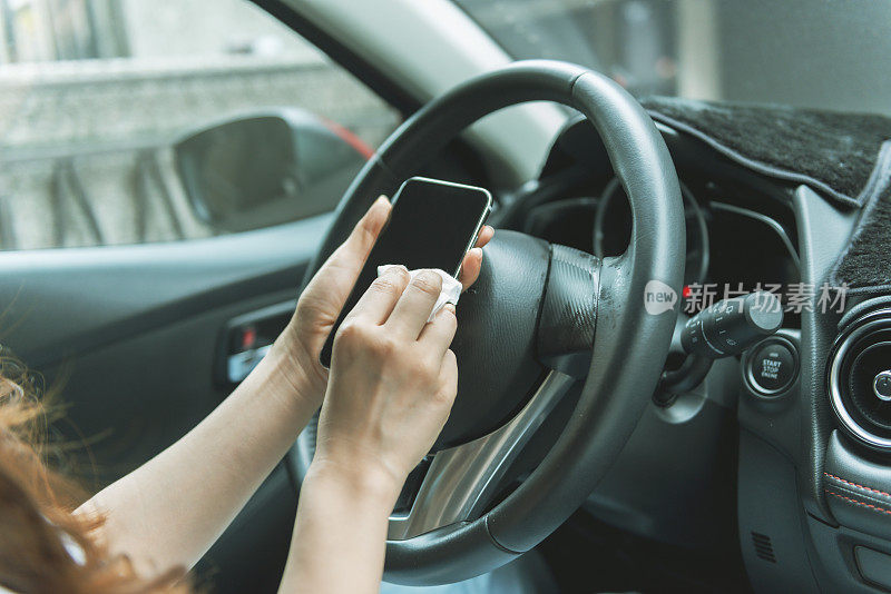 女人在车里用抗菌擦拭布清洁智能手机
