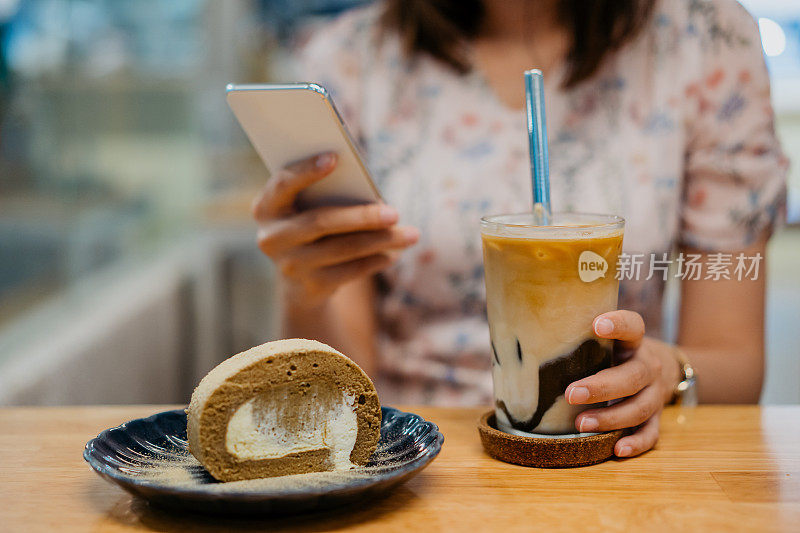 快乐的年轻亚洲女人在咖啡馆使用智能手机