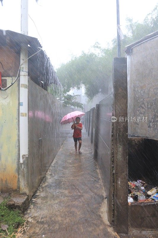 一个小女孩在倾盆大雨中带着雨伞。