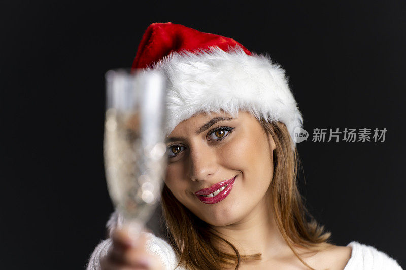美丽的年轻女孩与圣诞帽跳舞，而手持玻璃杯与香槟的黑色背景，圣诞节的心情