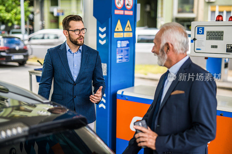 两个商人在加油站给汽车加油。