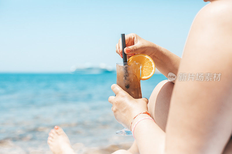 在海滩上喝着鸡尾酒的女人