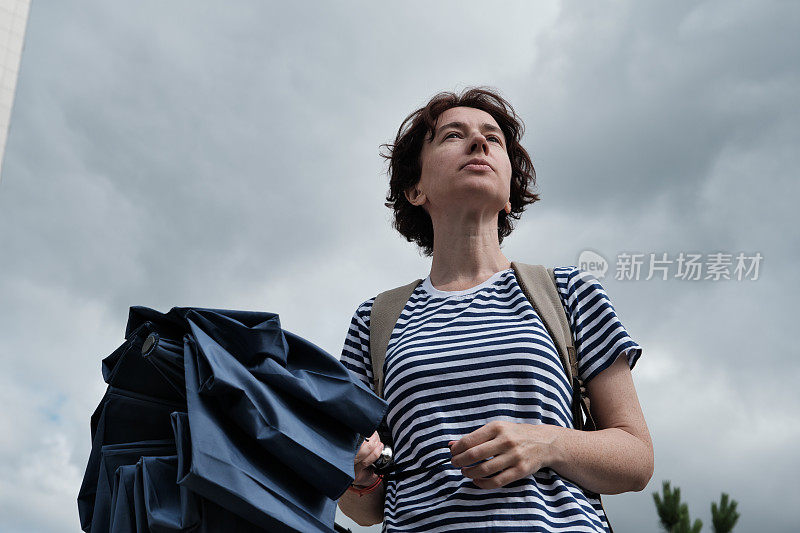 女人在看多云的天空，打着伞