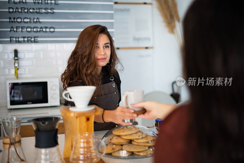 在咖啡店里，女咖啡师给他的女顾客递咖啡