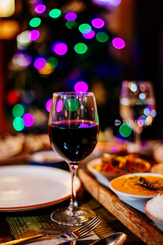 桌子上的红酒与圣诞桌子和树的特写。