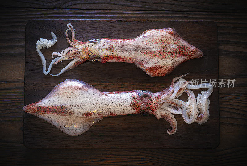 两片鱿鱼鱿鱼，新鲜海鲜，深色木质砧板
