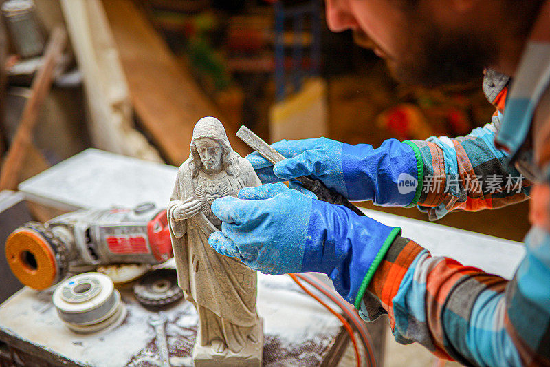 熟练的男性雕刻家，用手工工具在雕塑上雕刻小细节