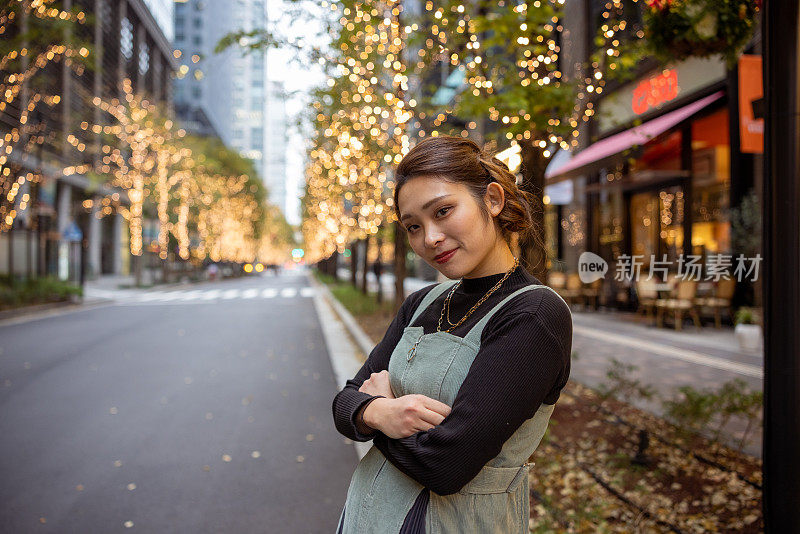 年轻女子的肖像站在街上与圣诞灯