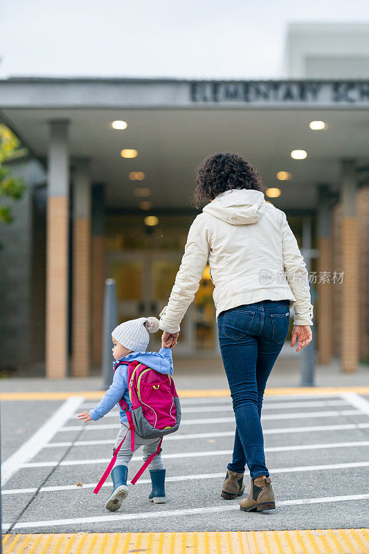 妈妈把蹒跚学步的女儿送到学校