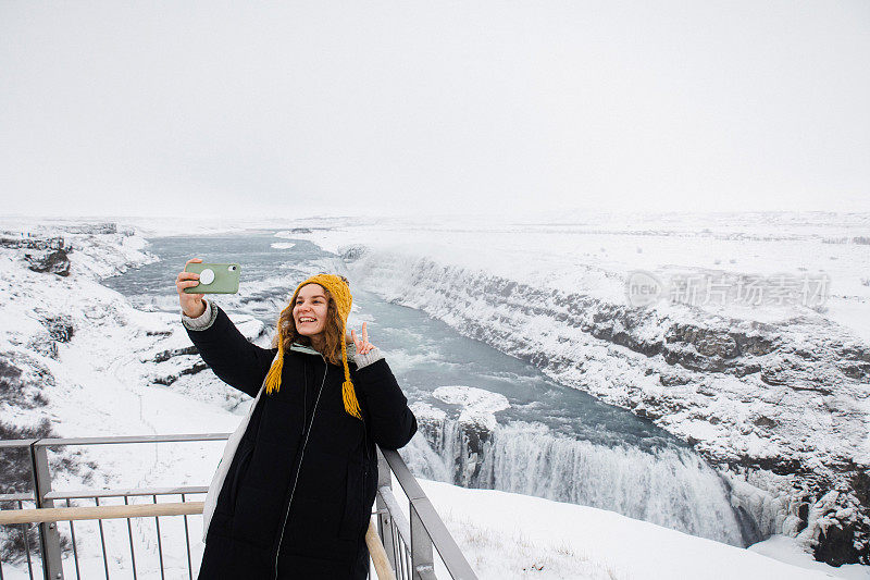 一个美丽的女人在风景优美的Gullfoss瀑布自拍