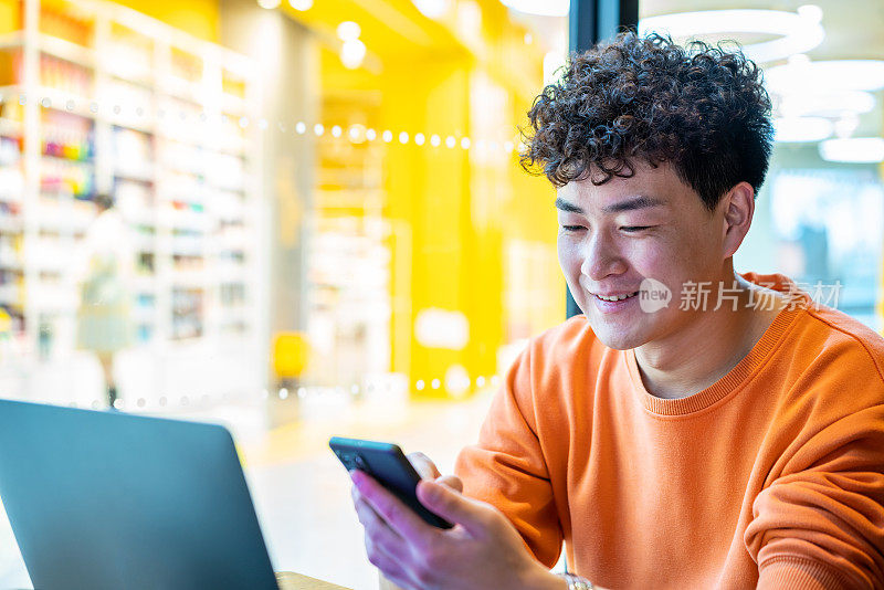 亚洲年轻帅哥在咖啡店用智能手机