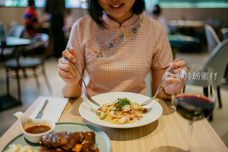 亚洲女人在餐厅吃奶油干酪意面