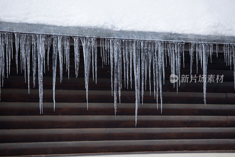 各种冰柱从雪覆盖的屋顶上垂下来