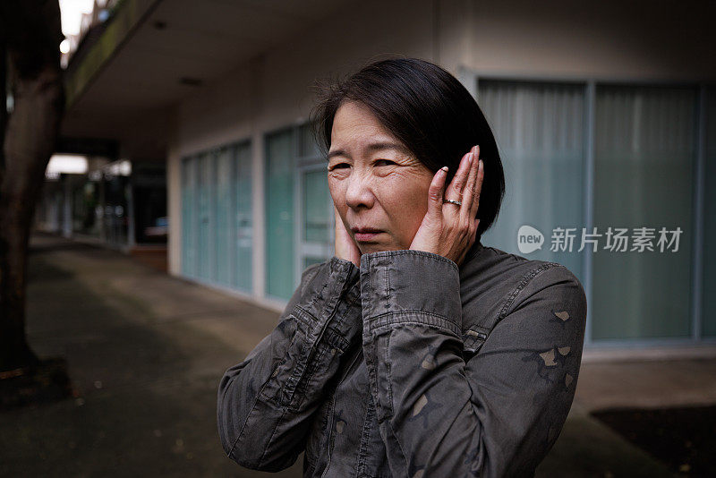 女人捂住耳朵。