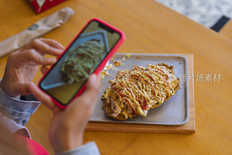 在一家餐厅用餐的拉丁裔顾客正在为她的餐盘拍照