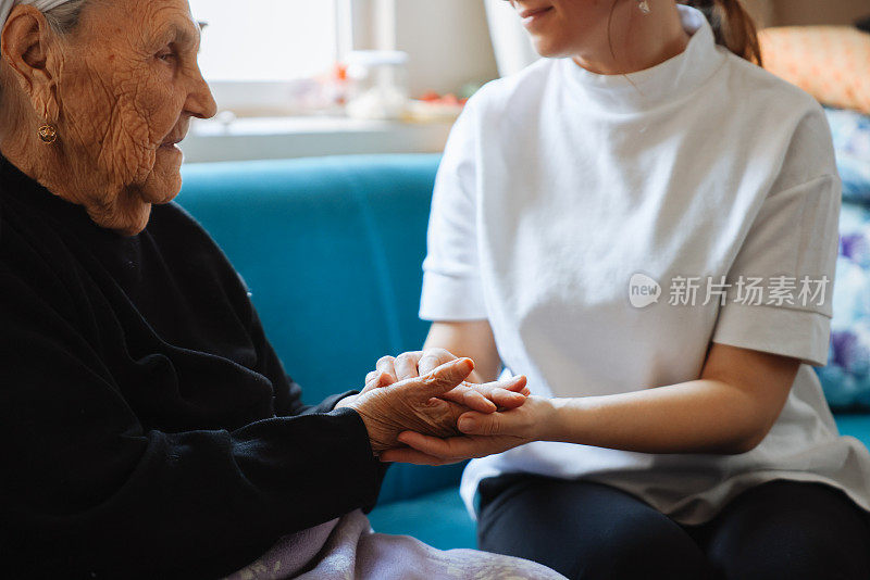 老女人的手牵着年轻女人的手，伸出援手，照顾老人的理念。