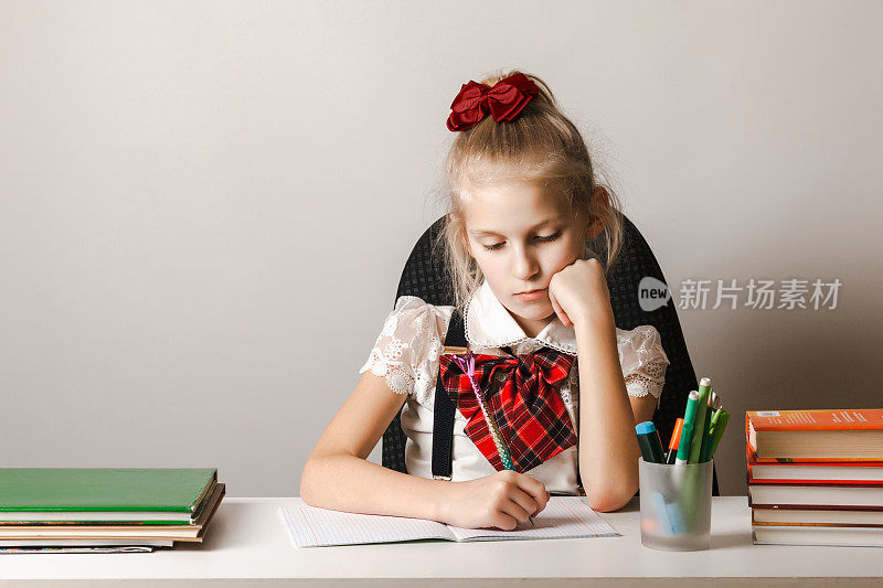 一个穿着校服的小女孩正在作业本上做家庭作业