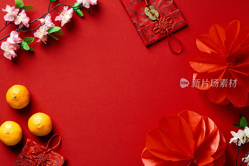 2023年春节快乐概念。红色的红包、橘子、鲜花和红色背景的灯笼。