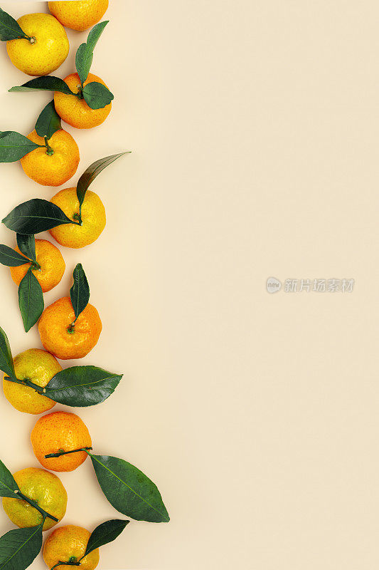 成熟的新鲜橙黄色橘子与绿叶在柔和的米色表背景与复制空间。柑橘类水果作为食物背景，留白，静物唯美